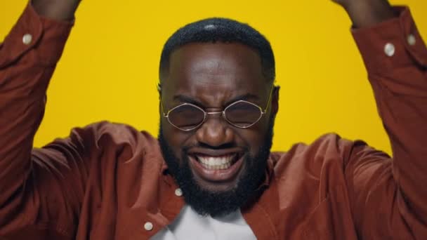 Portret van een gelukkige Afrikaanse man die de overwinning viert op een gele achtergrond. - Video