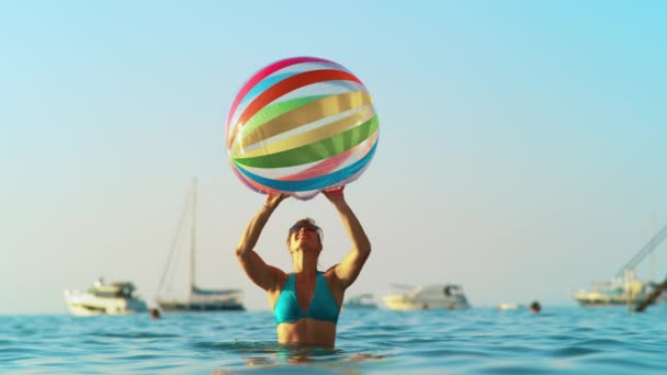 CLOSE UP: Junge Frau im Bikini spielt an sonnigem Abend mit riesigem aufblasbaren Ball - Filmmaterial, Video