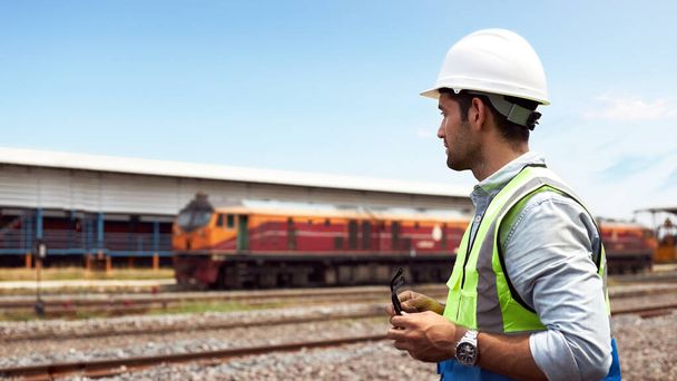 Başarılı demiryolu lojistik uzmanları ya da kask ve güvenlik yelekleri takan tren mühendisleri tren raylarında işlerinin hazır olup olmadığını kontrol etmek için bekliyorlar.. - Fotoğraf, Görsel