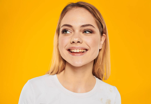 Glückliche blonde Frau lacht auf gelbem Hintergrund in weißem T-Shirt - Foto, Bild