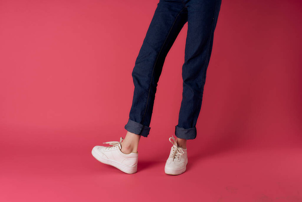 Damen Beine Jeans weiße Turnschuhe Straße Mode Studio rosa Hintergrund - Foto, Bild