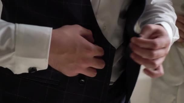 A young man buttons up his tuxedo jacket. Groom dresses for an event or wedding. - Metraje, vídeo