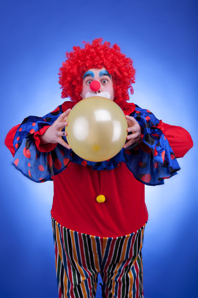 Clown mit Luftballon im roten Kostüm auf blauem Hintergrund - Foto, Bild