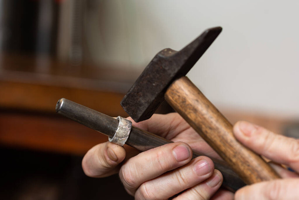 primer plano, martillo martillando un anillo de plata para darle forma en un taller de joyería. - Foto, imagen