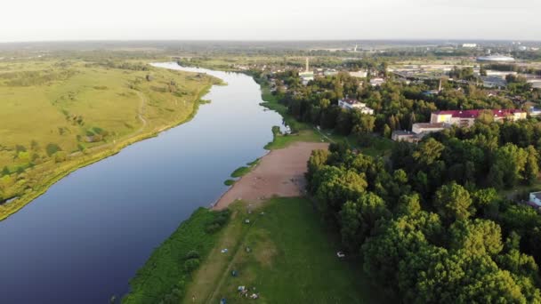 Vue aérienne de la ville de district parmi les arbres verts sur la rive de la rivière et les personnes au repos sur la plage de la ville - Séquence, vidéo