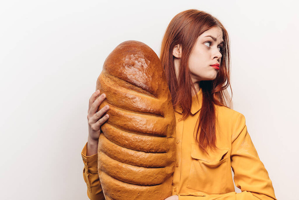 vörös hajú nő sárga ingben, kenyérrel a kezében liszt termék fény háttér Másolás hely - Fotó, kép