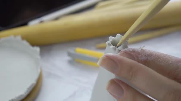 Mujeres manos esculpir detalles en arcilla blanca usando palo de madera. - Metraje, vídeo