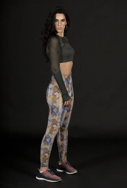 a vertical shot of a young Hispanic female posing with sportswear on the black background - Fotografie, Obrázek