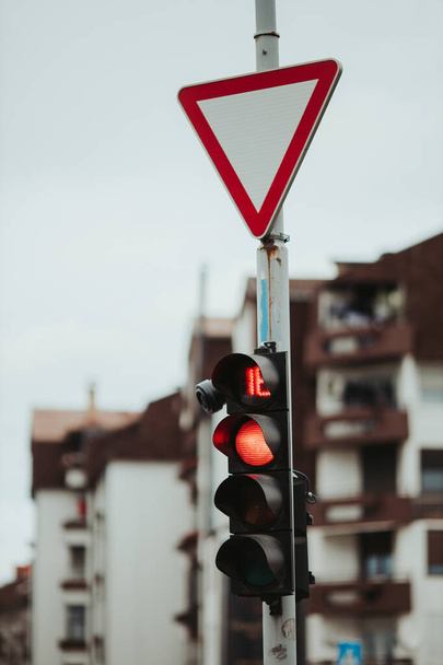 Μια κάθετη βολή ενός σήματος απόδοσης πάνω από ένα κόκκινο φανάρι - Φωτογραφία, εικόνα