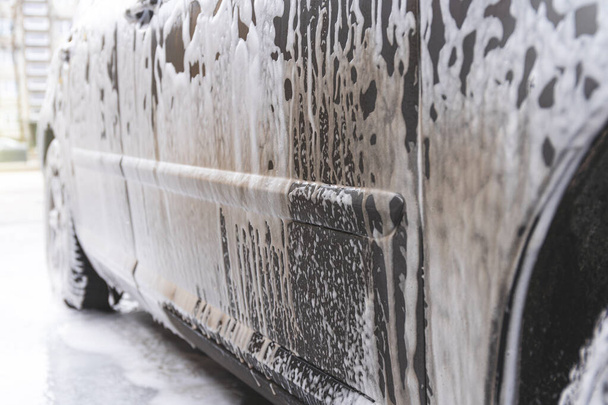 Coche cubierto con espuma de lavado en el servicio de lavado de coches sin contacto - Foto, Imagen