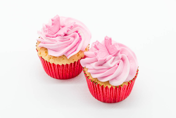 Pasteles de copa de Pascua dos en número con glaseado rosa y tripas de esponja roja sobre un fondo blanco. - Foto, imagen