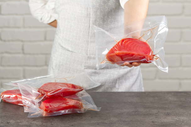un cocinero o un vendedor en un mercado de pescado que tenga un filete de atún rojo envasado en una bolsa de vacío - Foto, Imagen