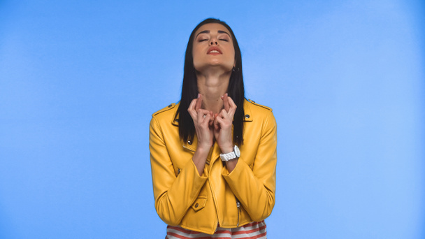 young woman with crossed fingers and closed eyes isolated on blue - Photo, Image