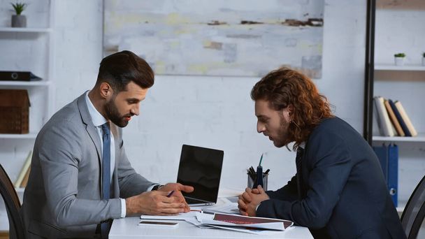 бизнесмен, указывающий на документы во время обсуждения с партнером в офисе - Фото, изображение