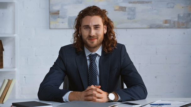 young businessman in suit smiling at camera while sitting at workplace - Photo, Image