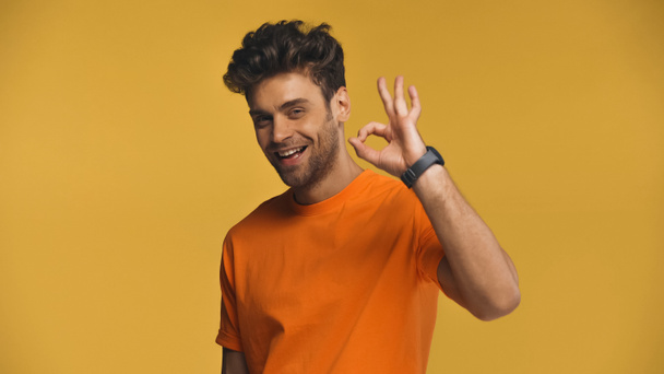 Glimlachende man toont goed gebaar geïsoleerd op geel - Foto, afbeelding