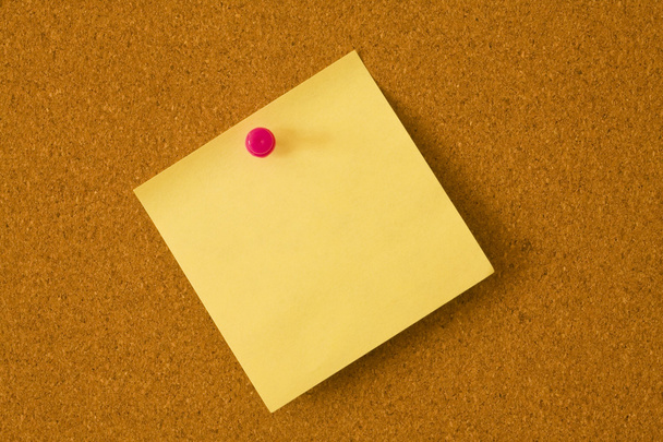 gelber Pfosten, der mit einem roten Stecknadeln an eine Pinnwand geheftet wird - Foto, Bild