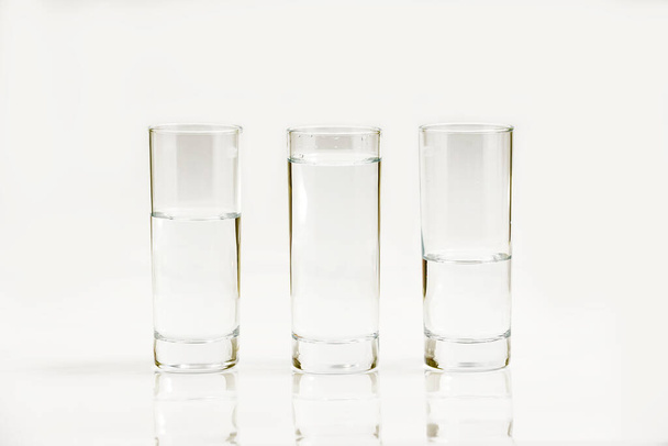 Water in three glasses - different level, isolated over a white background - three plastic bottles of water - Photo, Image