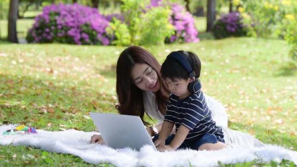 szczęśliwy Azji rodzina mając zabawy matka i jej syn za pomocą laptopa w parku razem - Materiał filmowy, wideo