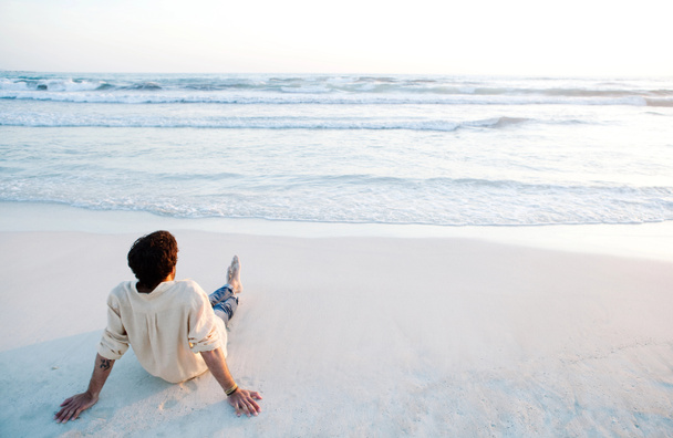 Nuori mies istuu rannalla
 - Valokuva, kuva