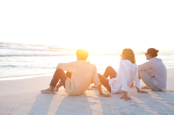 Amigos sentados na praia
 - Foto, Imagem