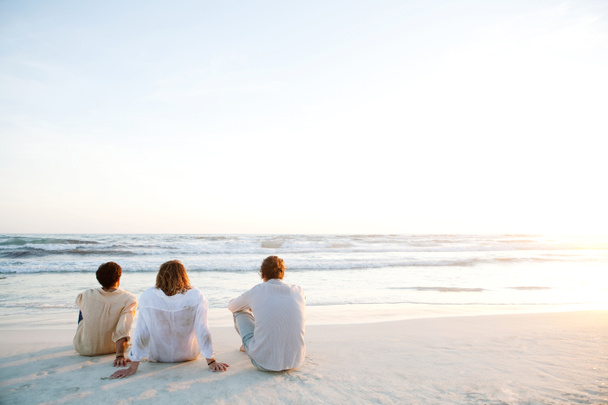 Amigos sentados en la playa
 - Foto, Imagen