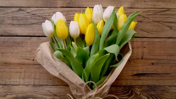 Yellow and white tulips bouquet on a wooden table top view  - Footage, Video