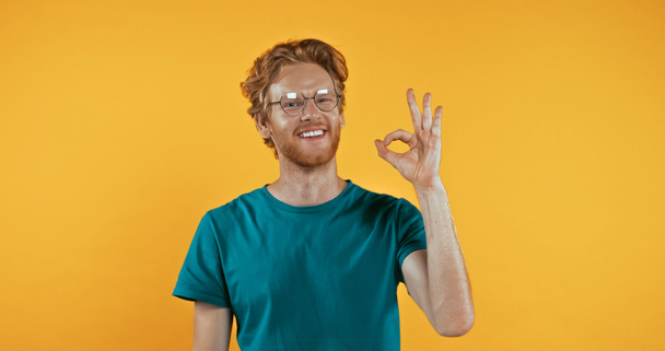 homem ruivo positivo em óculos mostrando sinal ok isolado no amarelo  - Foto, Imagem