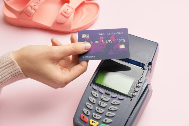 Női kéz hitelkártyával és fizetési terminál színes háttér, közelkép - Fotó, kép