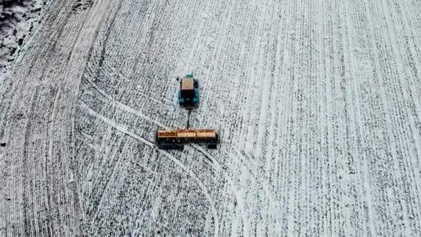 Die Düngung des Bodens und die Vorbereitung auf den Frühling mit dem Traktor, der auf einem landwirtschaftlichen Feld mit einer Schneeschicht im Winter arbeitet - Filmmaterial, Video