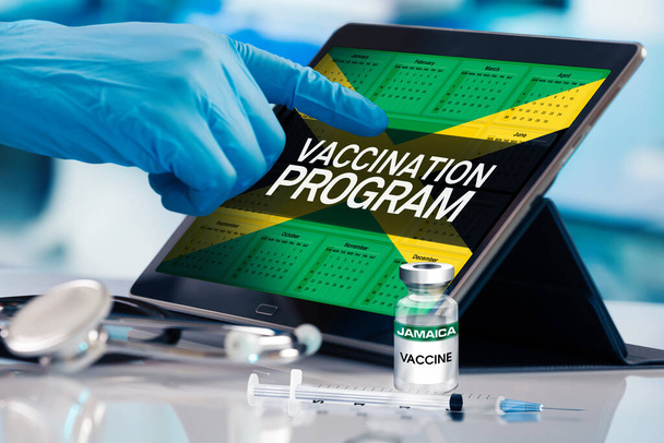 Επαγγελματίας που εργάζονται στο ημερολόγιο των εμβολίων σχέδιο για την Τζαμάικα έθνος, Ιμανοποίηση έννοια. Εργασία με δισκίο στο πρόγραμμα του προγράμματος εμβολιασμού για την Τζαμάικα. Photomontage με τρισδιάστατη απεικόνιση - Φωτογραφία, εικόνα