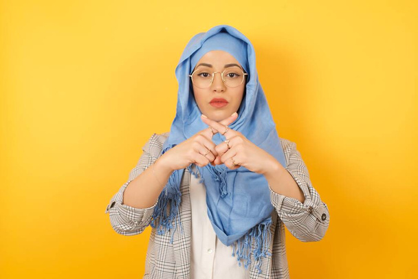 Giovane bella ragazza musulmana indossa hijab e vestiti casual, ha rifiuto, espressione arrabbiata incrociando le dita facendo segno negativo. Concetto di divieto. - Foto, immagini