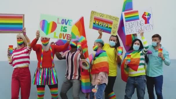 Happy Multiracial people wearing face mask celebrating at gay pride festival during corona virus - Group of friends with different age and race dancing together and fighting for gender equality - Footage, Video