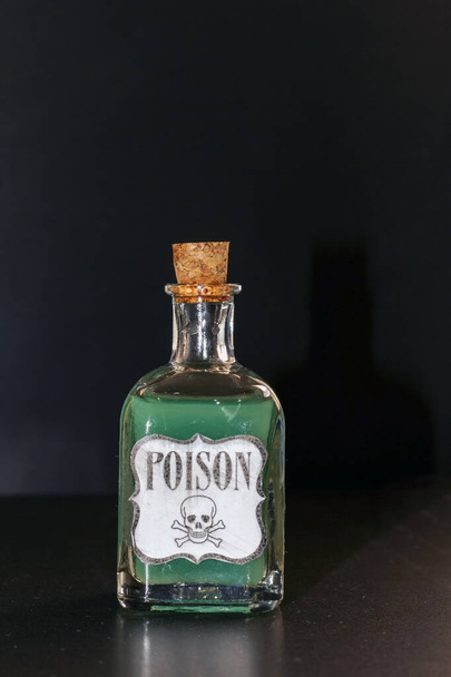 Koncepcja toksycznej rzeczy. Przezroczysta butelka z fioletową cieczą symulującą truciznę. Etykieta zawiera truciznę wraz z czaszką i dwoma piszczelami. - Zdjęcie, obraz