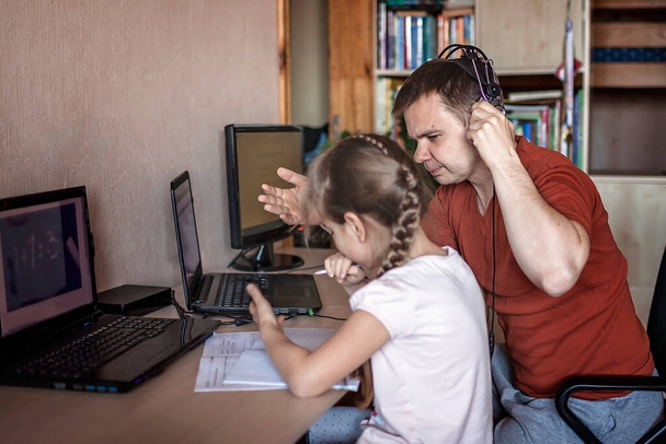 Um pai de meia-idade trabalhando on-line perto de sua filha bonito durante sua aula on-line em casa - Foto, Imagem