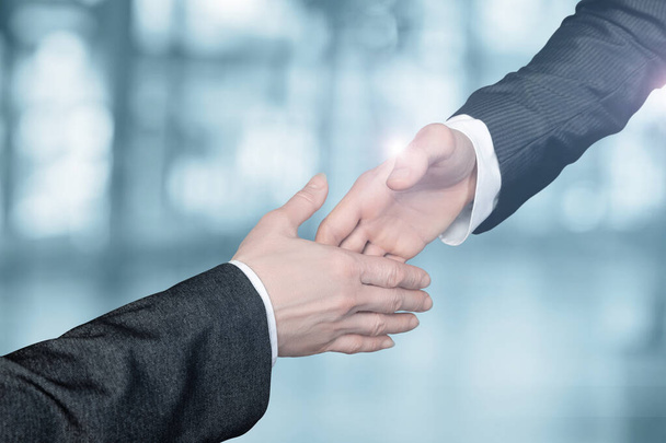 Empresários estendem a mão uns aos outros para apertar as mãos sobre um fundo turvo. - Foto, Imagem