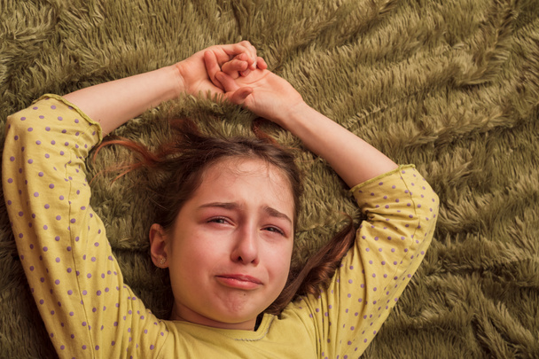 A lány depressziós az ágyban. A kislány sír. Könnyek a gyerek arcán. tini, szomorú, - Fotó, kép