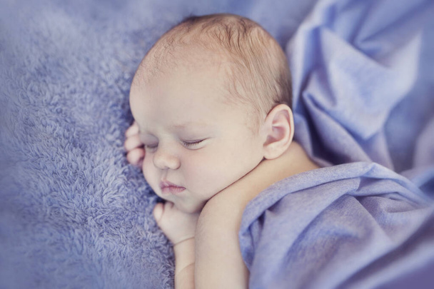 Новонароджена дитина спить на ковдрі. Час спати для немовляти. Крихітна дитина лежить на м'якій фіолетовій ковдрі
. - Фото, зображення
