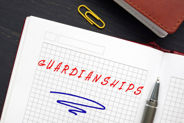 Business concept meaning GUARDIANSHIPS with phrase on the piece of paper. Guardianship is a legal process used to protect individuals who are unable to care for their own well-being due to infanc - Photo, Image