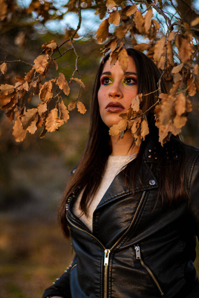 A shallow focus of a cool Hispanic female wearing a leather jacket and posing in a park in autumn - Φωτογραφία, εικόνα