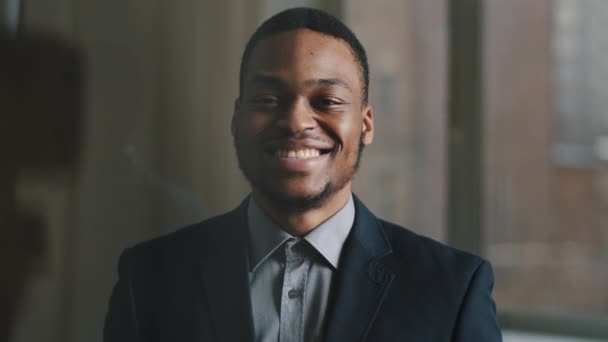 Frontansicht motivierter afroamerikanischer Geschäftsmann, junger Startup-Besitzer, der glücklich lächelnd zahm im Büroraum steht und mit dem Finger auf die Kamera zeigt, die zustimmende Geste macht, die Richtung oder Wahl anzeigt - Filmmaterial, Video