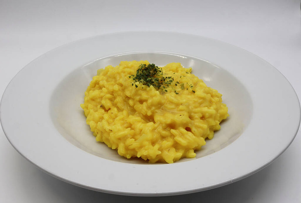 Risotto allo Zafferano italiano (arroz con azafrán) en un plato blanco - Foto, imagen