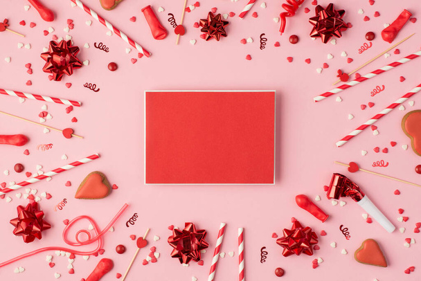 Top view fotó születésnapi összetétele piros szalaggal csillagok szerpentin konfetti szív alakú cookie-k fényes dekorációk és piros üres kártya sablon közepén pasztell rózsaszín háttér copyspace - Fotó, kép