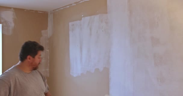 Βούρτσα κυλίνδρου με μακριά λαβή που εφαρμόζει λευκό χρώμα ασταριού στον τοίχο με ανακαίνιση σπιτιού - Πλάνα, βίντεο