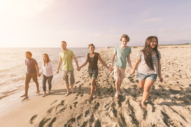 Многорасовая группа друзей, гуляющих на пляже
 - Фото, изображение