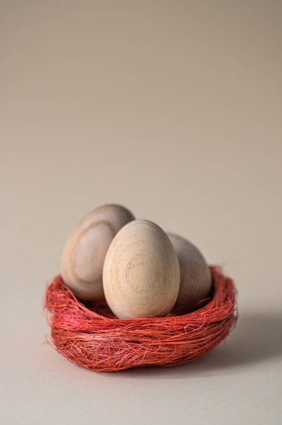 Пасхальные яйца в декоративном гнезде на нейтральном пастельном фоне. Минималистическая модная композиция крупным планом с пространством для текста. Поздравительная открытка  - Фото, изображение