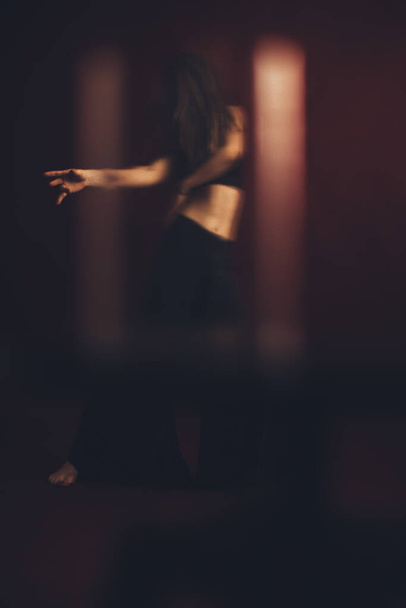 young model in dreadlocks actively dances and moves in the photo studio, the background is the color of burgundy and hot dancing - Foto, imagen