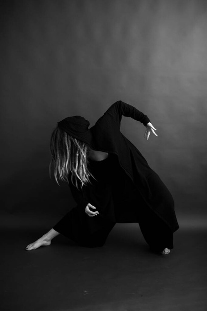 girl dancing in a black robe with a hood, art mystical photo - Φωτογραφία, εικόνα