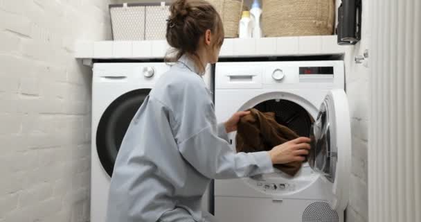 Mujer tomando ropa limpia y seca de la secadora - Imágenes, Vídeo
