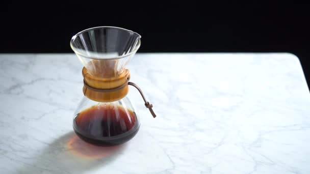 Side view of crop anonymous female pouring fresh hot brewed coffee prepared in glass jug into cup in cozy kitchen at home in slow motion - Footage, Video
